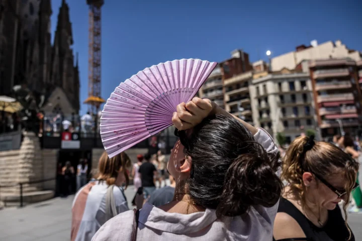 Una vianant es protegeix de la calor extrema amb un ventall davant la Sagrada Família (fotografia: Angel Garcia / Bloomberg).