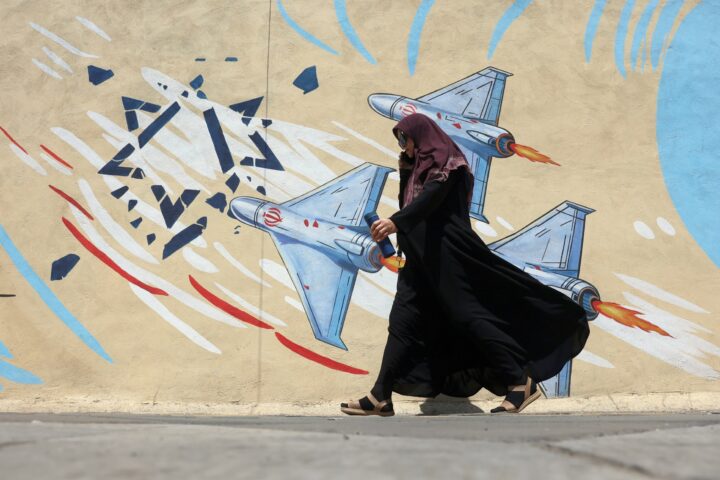 Una dona passa davant d'un mural bèl·lic a Teheran, la capital de l'Iran, a començament de mes (fotografia: Abedin Taherkenareh/Efe).