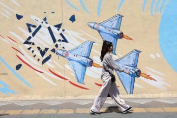 Una jove passa per davant d'un mural de propaganda bèl·lica a Teheran, la capital de l'Iran, ahir (fotografia: Abedin Taherkenareh/Efe).