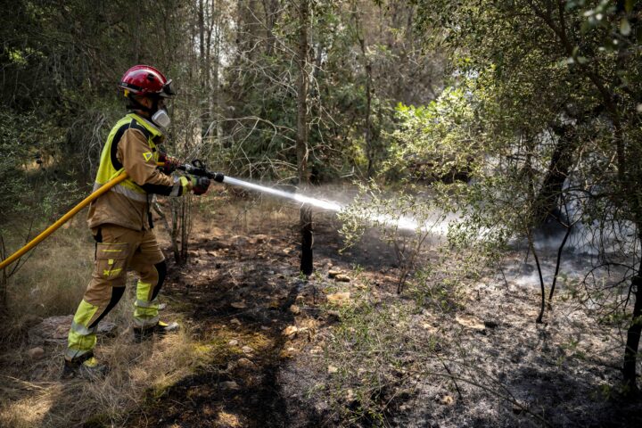 Un bomber treballa en les tasques d'extinció de l'incendi forestal a les muntanyes de Betxí per evitar la propagació d'un focus xicotet.