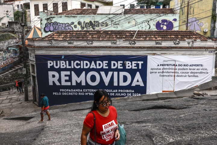 Vianants passen davant un cartell que anuncia la retirada de publicitat d'una casa d'apostes a O Rio de Janeiro, la setmana passada (fotografia: André Coelho/Efe).