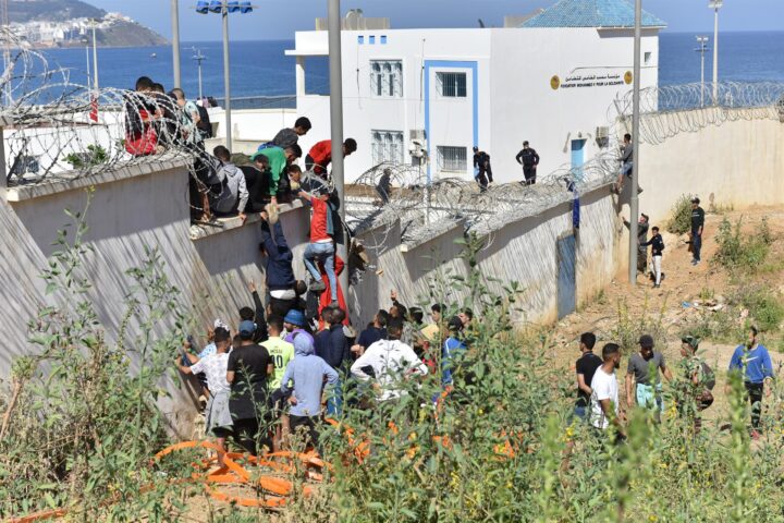 Arxiu – Migrants escalen la tanca fronterera per entrar a l’enclavament espanyol de Ceuta, a Fnideq (Marroc), el 18 de maig de 2021. Fotografia: Europa Press/Contacto/Xinhua