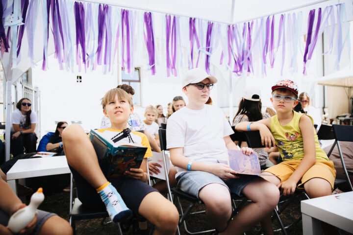Uns nens escolten un recital de poesia, una mica escèptics, amb llibres en ucraïnès a les mans (fotografia: Tetiana Shavlovska).).
