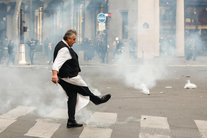 Un cambrer aparta un pot de fum disparat per la policia, dissabte a París (Fotografia: Mohammed Badra)