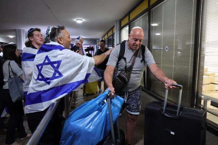 Un passatger del vol 1073 de Flydubai és saludat per homes que porten banderes d'Israel a l'arribada de l'avió a Tel-Aviv, dimecres a la nit, hores després de l'intent de segrest (fotografia: Abir Sultan / Efe).