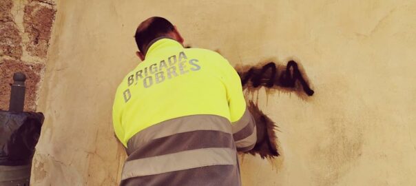 Un operari de la brigada d'obres neteja una de les pintades realitzades al Palau d'Albaida